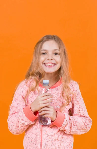 Klein meisje glimlach met water fles op oranje achtergrond — Stockfoto