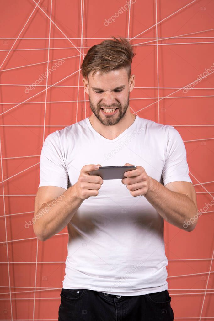 Excited about gaming. Guy play game smartphone gadget. Gamer aggressive face play online game smartphone. Application for smartphone concept. . Game addiction concept. Man not inseparable from phone