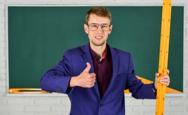 Matematik ve insanlar kavramı. Tahtadaki adam. Okula dönüyorum. Bilgiye doğru. Geometri favori konusu. Erkek öğretmen matematik cetvelini tutuyor. Eğitim ve okul konsepti. kök okul disiplinleri