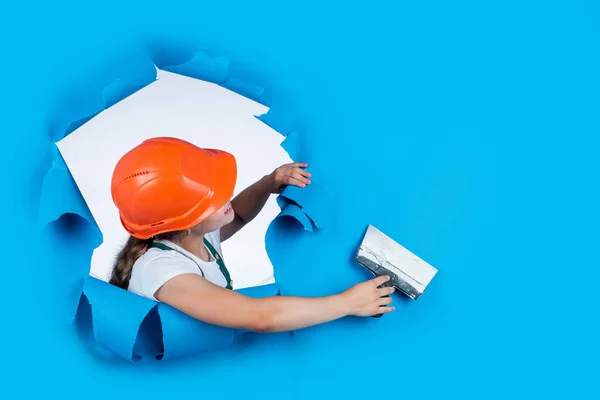 Glückliches Mädchen, das mit Spachtel arbeitet. kleiner Bauarbeiter mit Spachtelmesser. Kind mit Helm und Spachtel. Maurerkind mit Helm und Spachtelkelle. Haussanierung. Kopierraum — Stockfoto