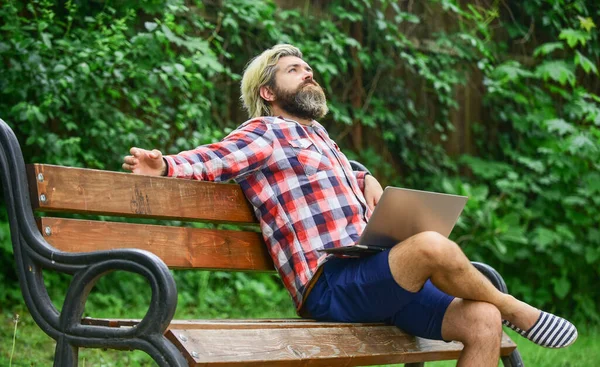 Hipster inspired work in park. Modern laptop. Remote job. Fresh air. Mobile internet. Online shopping. Agile business. Bearded guy sit bench park nature background. Work and relax. Working online