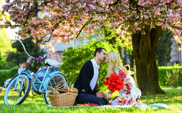 Glad att vara kär. romantiska par på picknick. Kärleksdejt på våren. Koppla av under blommande sakura. par förälskade. firar årsdagen. lycklig familj i sommarparken. mat och dryck. man och kvinna — Stockfoto