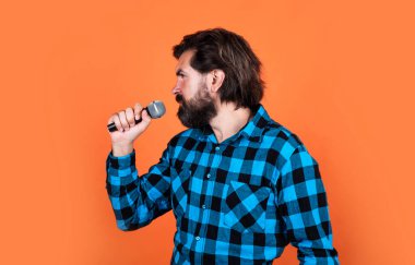 Etkinlik yöneticisi. Mikrofonlu adam. Müzik konsepti. Kareli gömlek giyen şarkı söyleyen adam. Karaoke kulübünde kendine güvenen bir erkek şarkıcı. Parti performansı. Sakallı hippi mikrofonda şarkı söylüyor.