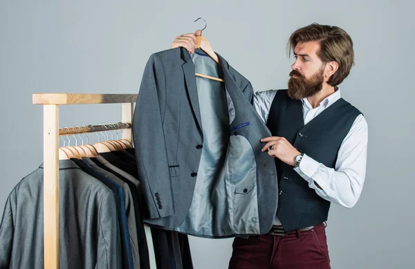 Bearded man customer looking for his size formal suit, seasonal sale concept