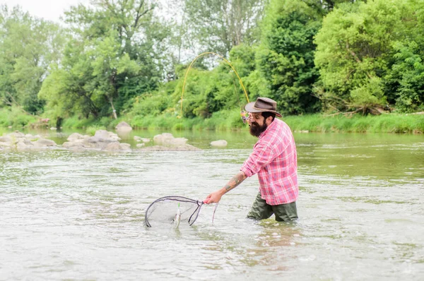 Bobina Pesca sportiva. uomo maturo pesca a mosca. uomo cattura il pesce. hobby e attività sportive. Pothunter. weekend estivo. Pesca d'altura. pescatore barbuto in acqua. pescatore con canna da pesca — Foto Stock