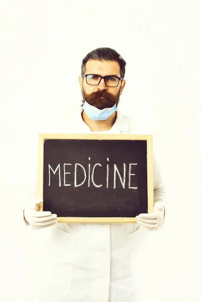 Médico caucasiano barbudo segurando seringa e papelão com inscrição em Medicina — Fotografia de Stock