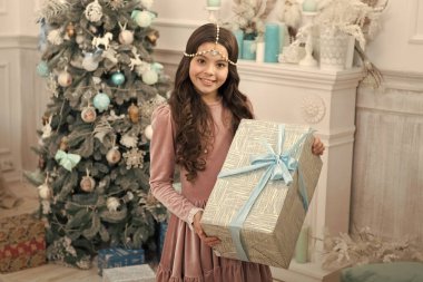 Yeteneği için heyecanlı bir çocuk. Zarif elbiseli küçük kız ve hediye kutusu Noel ağacı arkaplanı. Noel hediyesi. Küçük kız bayram hediyesi aldı. En iyi Noel hediyeleri. Kış sürprizi