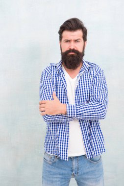 Tıraşsız sakallı, sıradan moda tarzı olan, kollarını çapraz mavi arka planda tutan hippi sakallı adam.