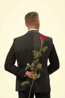 Sürpriz. Sevgililer günün kutlu olsun. Erkek resmi moda. Yakışıklı adam Rose 'u arkasına sakladı. Romantik bir randevu için hazırlan. Resmi etkinlikler için siyah kravat. Güllü smokin giyen adam. gizli sevgililer günü