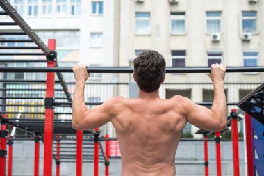 Adam kaslı sırt sporcusu düzgün formda barfiks çekiyor, spor konsepti.