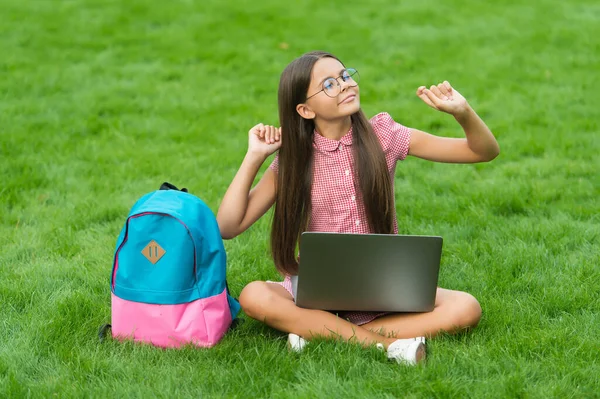 Fritid. Tillbaka till skolan. utbildning på nätet. Kunskapsdag. Han lär sig privatlektioner. Jag bloggar. bekymmerslös flicka sitter på grönt gräs med bärbar dator. Börja. spela dataspel för barn — Stockfoto