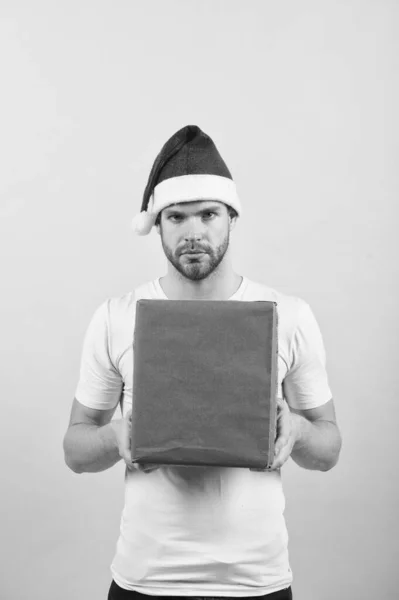 Teslimat servisi. Kurye işi. Dilek listesi. Yakışıklı bir adam Noel Baba şapkalı hediye kutusu giyer. Hipster Noel hediyesini saklar. Hediye vermek mutluluğu yayar. Tebrikler. Noel selamları — Stok fotoğraf