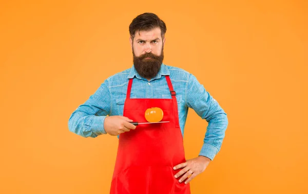 Sérieux pour la nourriture. Un barbu tient une tomate sur un couteau. Cuisiner de la nourriture végétarienne. Légumes bio. Une saine alimentation. Nutrition naturelle. Régime alimentaire et régime — Photo