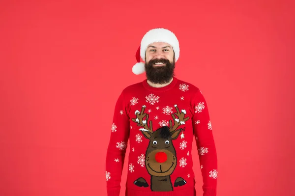 Happy new year. cheerful hipster funny knitted sweater. warm clothes in cold winter weather. holiday season mood. bearded man santa hat red background. merry christmas. ready for xmas party — Stock Photo, Image