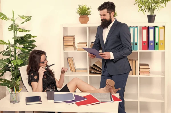 Patron ve çalışan. Kadın egemenliği. Erkek kadına karşı. İş yerindeki iş çifti. Erkek asistan çalışırken kendine güvenen iş kadını rahatlar. İş adamı tembel sekretere talimat verdi