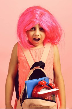 Pembe arka planda pembe peruklu okul üniformalı bir öğrenci.
