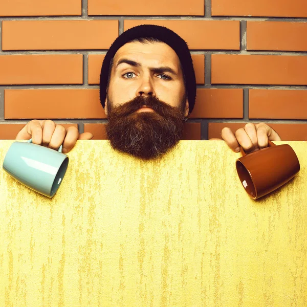 Barbudo brutal hipster caucásico con hoja de papel y tazas —  Fotos de Stock