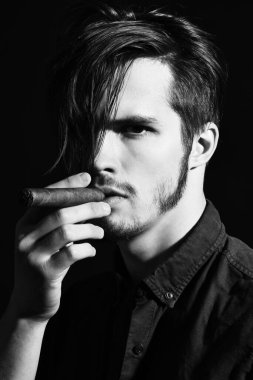 Ciddi sakallı adam puro içiyor.