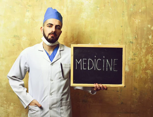 Chico en uniforme médico sostiene pizarra con palabra medicina —  Fotos de Stock