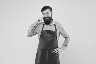 Hazırlık ve aşçılık. Olgun bir barmen. Yeni işini. Tezgahtar üniformalı adam. Sarı arka planda kırmızı önlüklü gülümseyen adam. Kendine güvenen ifade. Yakışıklı erkek barista çalışıyor.