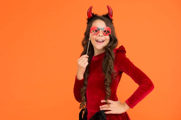 Grappig kind in heks kostuum hoed voor Halloween met party bril en duivel hoorns op oranje achtergrond, Halloween feest — Stockfoto