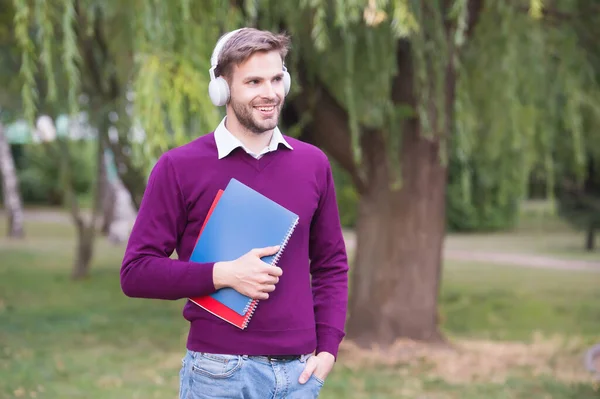 Collège moderne étudiant debout dans le parc écouter de la musique avec écouteur et livre de lecture, la vie des étudiants — Photo