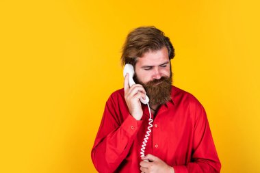 Sohbet için üzgünüm. Retro telefonlu, sakallı, olgun bir hippi. Kafkasyalı vahşi adam telefonda konuşuyor. İletişim konsepti. Telefona sakallı adam cevap verdi. Yakışıklı adam konuşuyor.