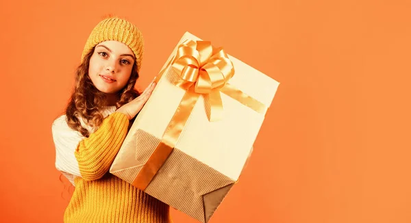 Guarda un po '. piccola ragazza a maglia cappello e maglione. bambino tenere presente casella sfondo arancione. felice anno nuovo 2020. servizio di consegna regalo. vantaggi dello shopping. Natale e 'qui. sorpresa vacanza invernale — Foto Stock