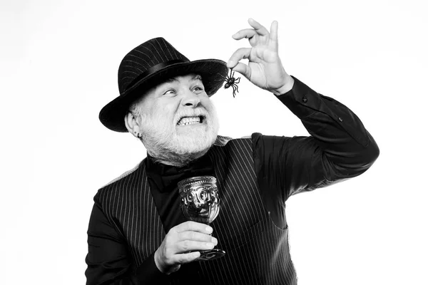 Disgusting Halloween drink. Elegant bartender wear hat and vest. Halloween concept. Add spider cocktail recipe. Halloween party. Weird old grandfather with gray beard eating spider. Exotic food — Stock Photo, Image