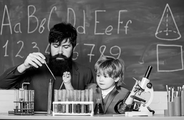 bearded man teacher with little boy. laboratory research and development. father and son child at school. Laboratory test tubes and flasks with colored liquids Chemistry beaker experiment