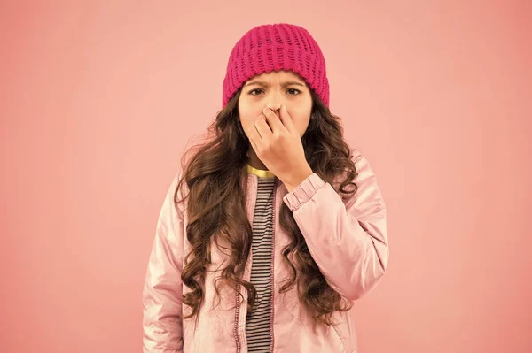 Flu season. Sneezing. Cold climate weather. Little girl sick ill pink background. Kid puffer jacket and knitted hat. Winter cold flu. Health care. Feeling bad. Medical treatment. Flu remedies