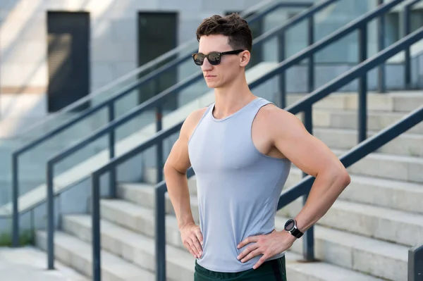 Мотивированный молодой спортсмен в солнечных очках, готовый к утренней пробежке на стадионе — стоковое фото