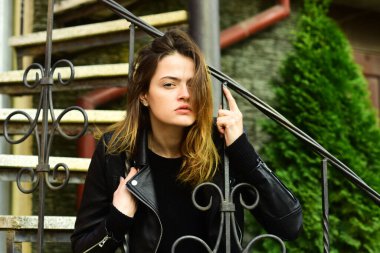 Kurnaz yüzlü kadın taş merdivenlerde oturuyor.