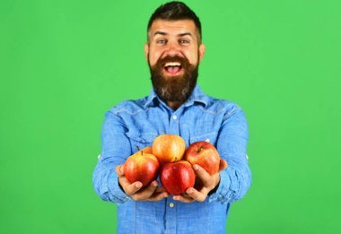 Sakallı adam yeşil arka planda kırmızı meyveler tutuyor.