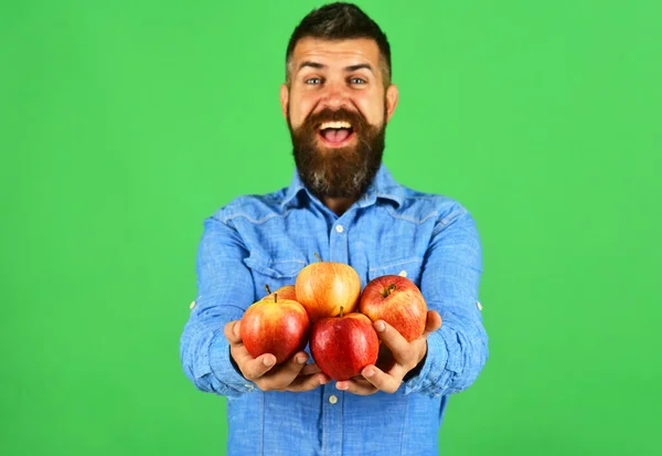턱수염이 있는 사람은 녹색 배경에 고립 된 빨간 열매를 갖고 있다 — 스톡 사진