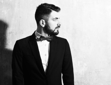 Stüdyo duvarında ciddi bir yüzü olan sakallı bir adam.