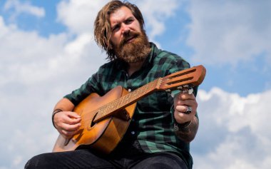 Benim dünyam burası. Olgun karizmatik erkek gitarist. Sakallı ve bıyıklı adam gitar çalıyor. Kareli gömlekli sakallı adam şarkı söylüyor. Müzisyen müzisyen. müzik teli enstrümanı