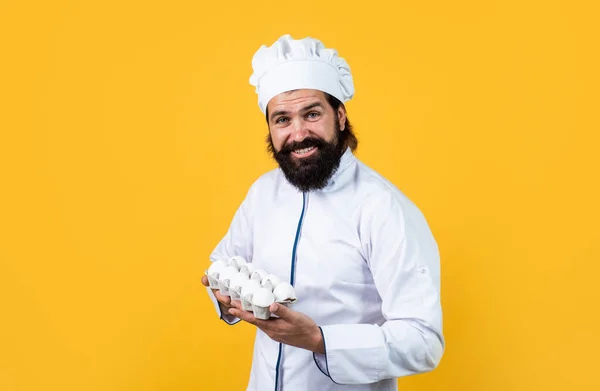 Brutale man met snor en baard in uniforme kookeitjes, natuurlijke producten — Stockfoto