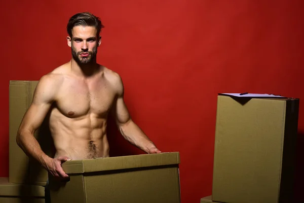 Guy with sexy naked torso holds box in front.