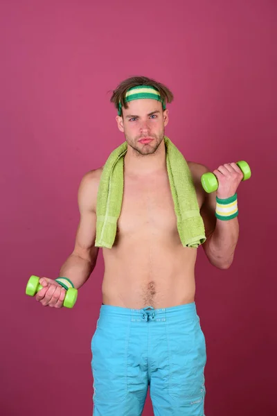 Hombre con torso desnudo sostiene toalla en el cuello y mancuernas — Foto de Stock