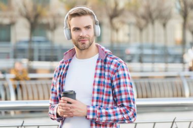 Taze kahveyle ısınıyorum. Kulaklıklı adam, ses kitabını dinle. İş adamı dışarıda çalışıyor. Açık havada kahve içen şık giyinmiş biri. Beyaz erkek sokakta dinleniyor ve müzik dinliyor.