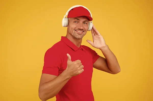 Audio guide. Man in headphones on yellow background. Assistant call center help find solution. Guy call service worker. Man listen music headphones. Incoming call. Worker in uniform with earphones — Stock Photo, Image