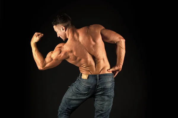 Starker Bodybuilder, der die Arme muskulös lässt, schwarzer Hintergrund. Fitter Bodybuilder mit muskulösem Körper. Professionelle Trainer zeigen Leistungen. Übungen für den Rücken. Bodybuilder perfekt in Form Rückansicht — Stockfoto