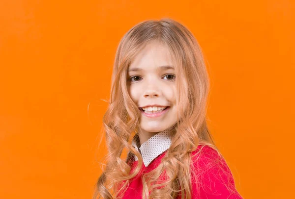 Criança com cabelo louro encaracolado no fundo laranja — Fotografia de Stock