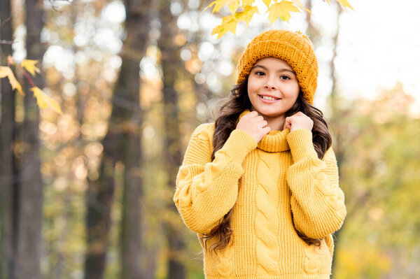 Autumn joy. small girl wear knitted hat and sweater. child enjoy fall weather in forest. kid in park. girl fall clothes fashion. beauty style. happy kid relax in autumn nature