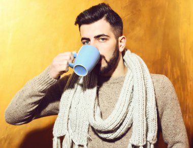 Sakallı adam çay içiyor, fincandan kahve içiyor.