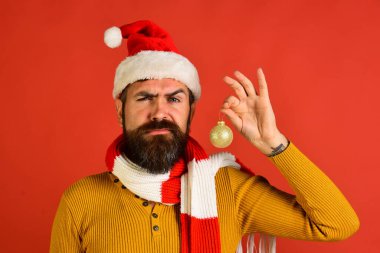 Noel Baba kırmızı arka planda köknar ağacı için topu tutuyor.