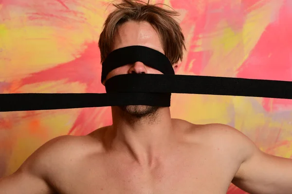 Man with covered face and naked torso on colorful background.