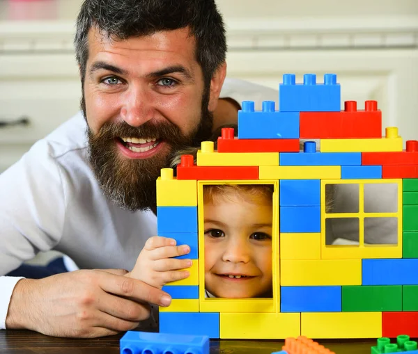 Padre e hijo con caras sonrientes sostienen construcción de ladrillos de juguete — Foto de Stock