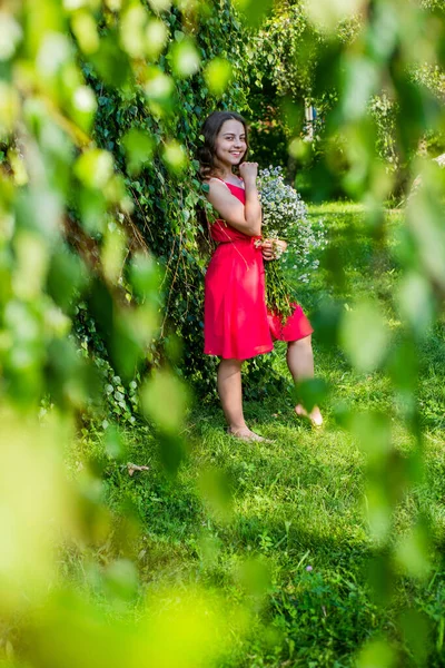 행복 한 작은 아기 아기는 자연 경관에 여름 꽃을 들고 있는 빨간 드레스를 입는다 — 스톡 사진